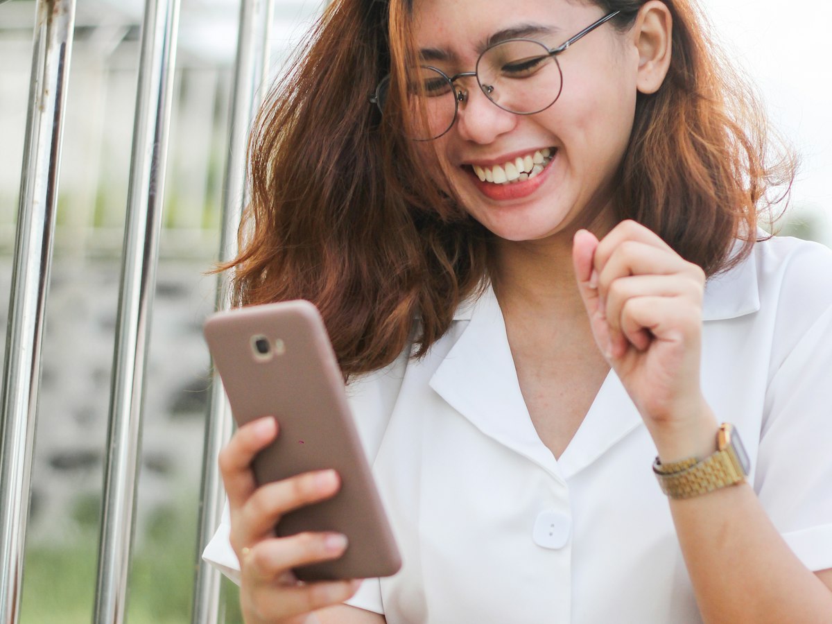 A smiling woman sending a photo from her phone